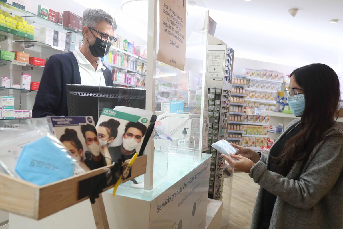 Una joven adquiere un paquete de mascarillas en una farmacia