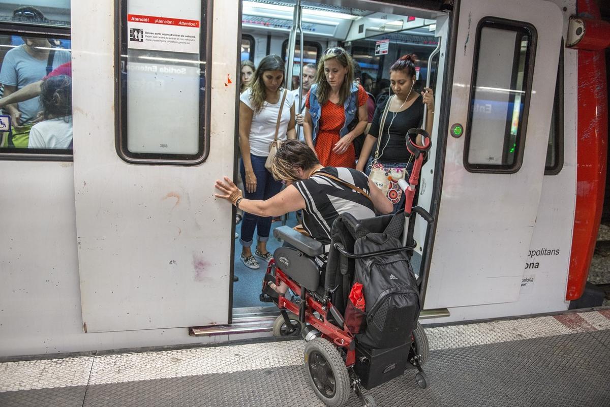 Una mujer en silla de ruedas intenta acceder al vagón del metro.