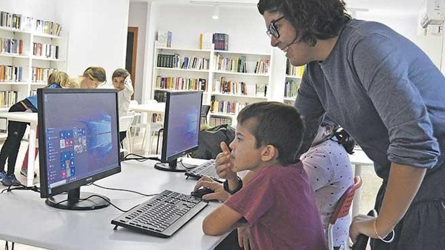 Imagen de varios niños atendiendo a una monitora en las instalaciones de la nueva biblioteca.