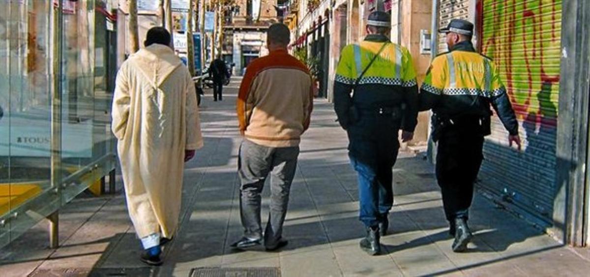 Immigrants i agents de la Guàrdia Urbana es passegen per la rambla del Raval, divendres passat.