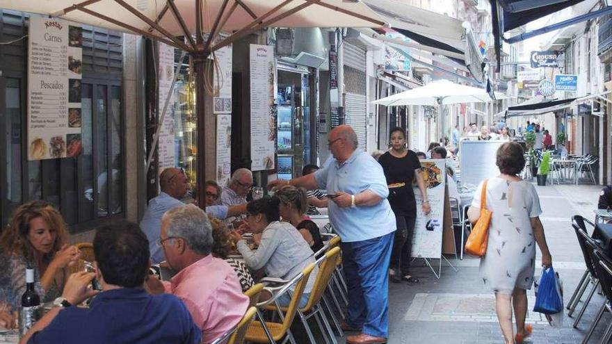 Un camarero atiende a unos clientes en una terraza de Santiago.