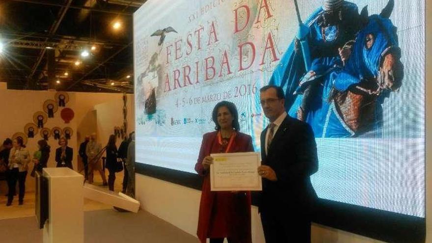 La secretaria de Estado de Turismo, Isabel Borrego, entrega la distinción al alcalde baionés, Ángel Rodal, en el estand de Galicia.