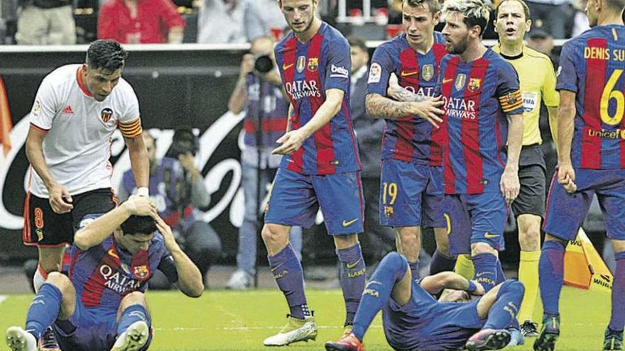 Suárez y Neymar se duelen en el suelo del botellazo recibido en Mestalla. // Efe