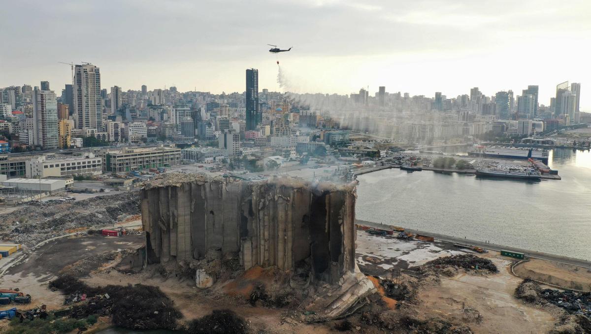 Una imagen aérea muestra a un helicóptero del ejército libanés soltando agua sobre los silos de grano fuertemente dañados en el puerto de la capital, Beirut, el 31 de julio de 2022, tras el colapso parcial debido a un incendio que se está produciendo desde principios de mes.