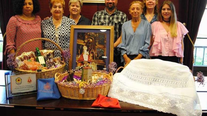 Por la izquierda, Maribel Reyes (banda de música), Rosa Delclós, la edil Pilar Cuesta, Manuel García (banda de gaitas), Amparo Antuña, Michelle Herron (banda de música) y Nara Teijeiro, con la ofrenda.