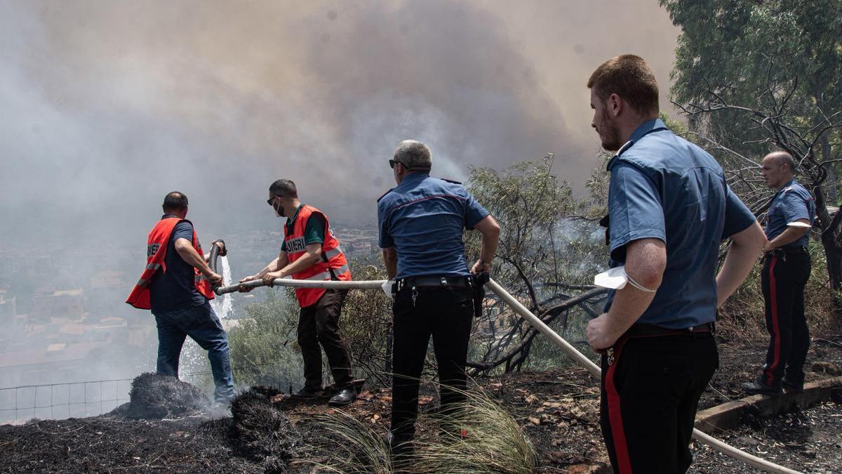 Bomberos intentan apagar los incendios que rodean la ciudad de Palermo, en Sicilia.