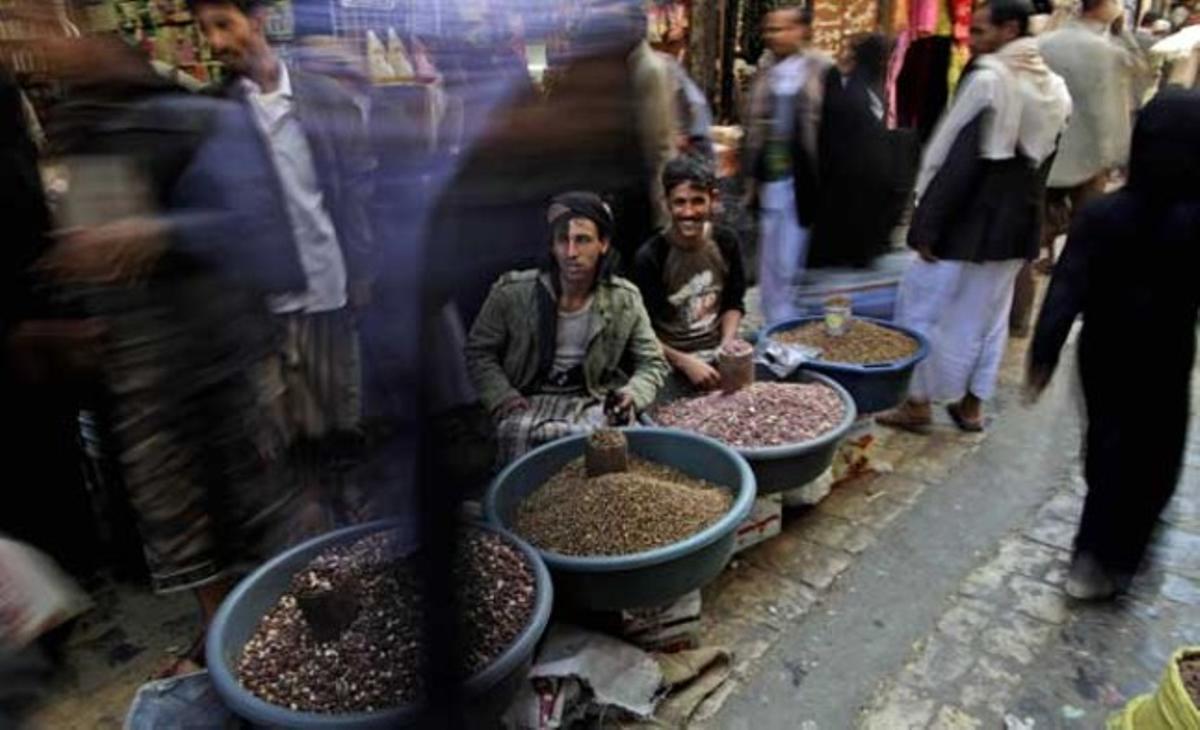 Ciutadans iemenites passegen davant de dos venedors de fruita seca al mercat de la ciutat antiga de Sanà.
