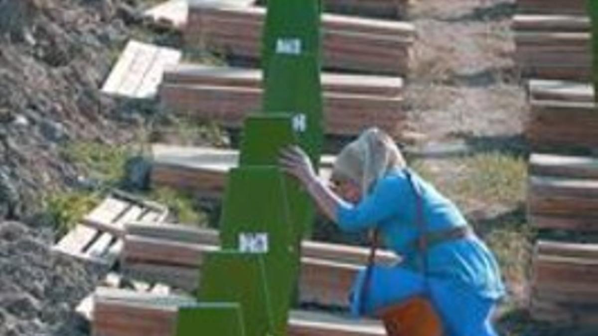 Una mujer musulmana llora ante la tumba de un familiar rodeada de féretros, ayer en el Memorial de Potocari.