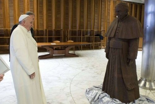 Pope Francis looks at a chocolate statue made in his likeness, which he received as a gift, in Paul VI's Hall at the Vatican