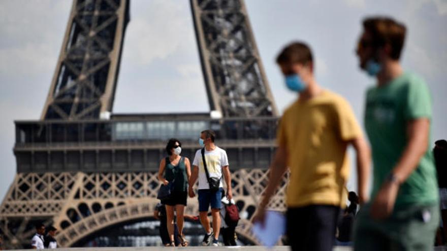 Vista parcial de la torre Eiffel, en París, con personas con masccarilla