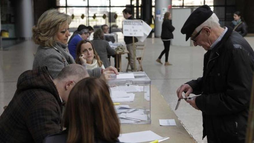 Un gijonés extrae su carné de identidad para ejercer su derecho al voto en una mesa electoral instalada en la estación de Pedro Duro.