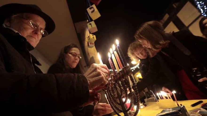 Varios fieles encienden sus candelabros en la plaza del Fontán.