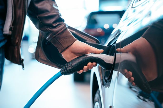 Un hombre cargando un coche eléctrico