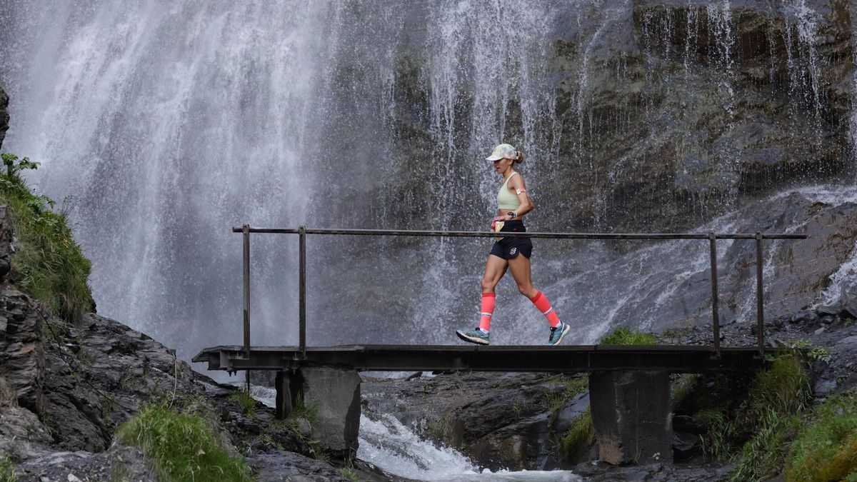 Una participante pasa por un puente con una cascada detrás en la Vuelta a Cerler.