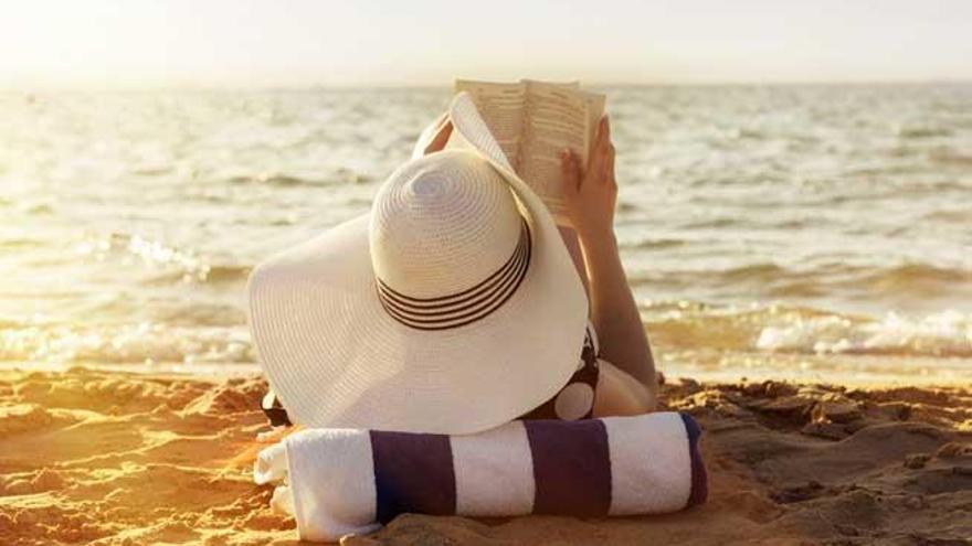 Una mujer lee un libro en la playa.