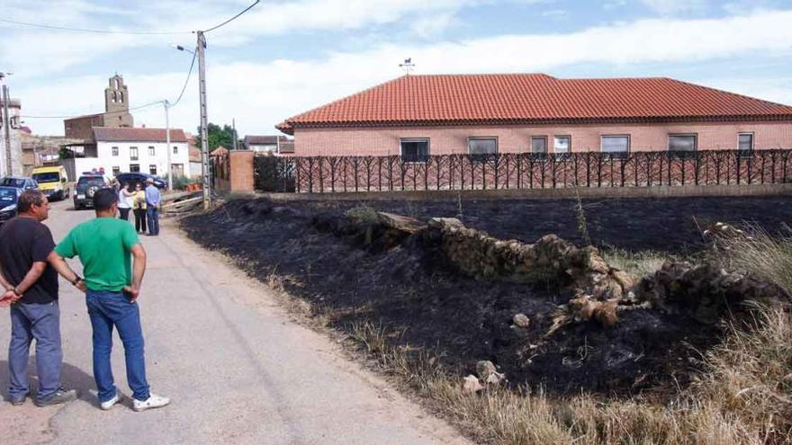 Los vecinos de Vega de Villalobos observan los daños causados por el fuego en la vivienda y el terreno.