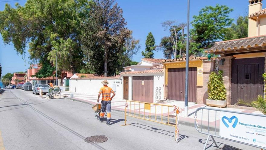 Dos operarios de la Delegación de Obras arreglan una calle en Marbella.