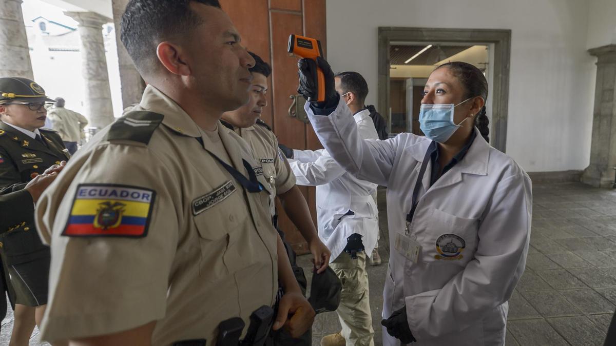 Personal médico comprueba la temperatura de varios agentes de la Policía de Ecuador, en medio de la crisis sanitaria de la covid-19.