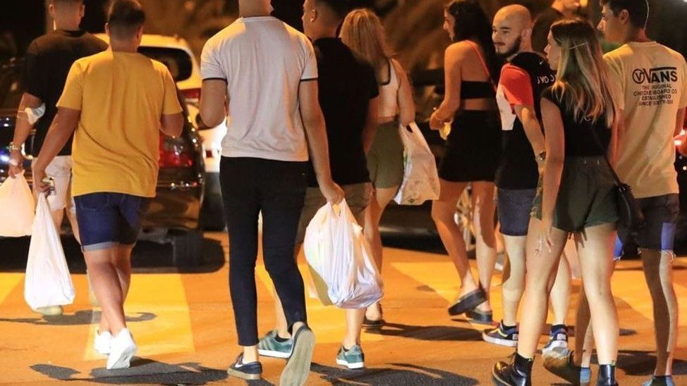 Jóvenes con bolsas de bebida preparados para hacer botellón.