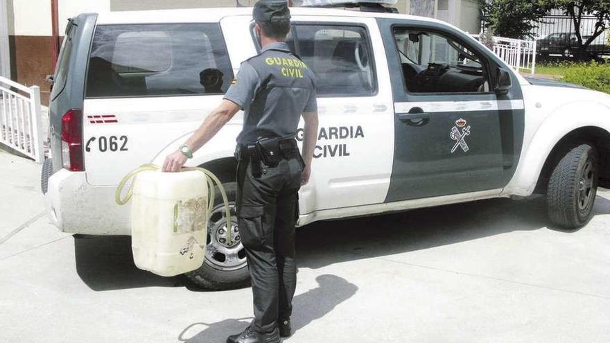 Un guardia civil sosteniendo la garrafa que fue encontrada en el lugar de los hechos.  // FdV