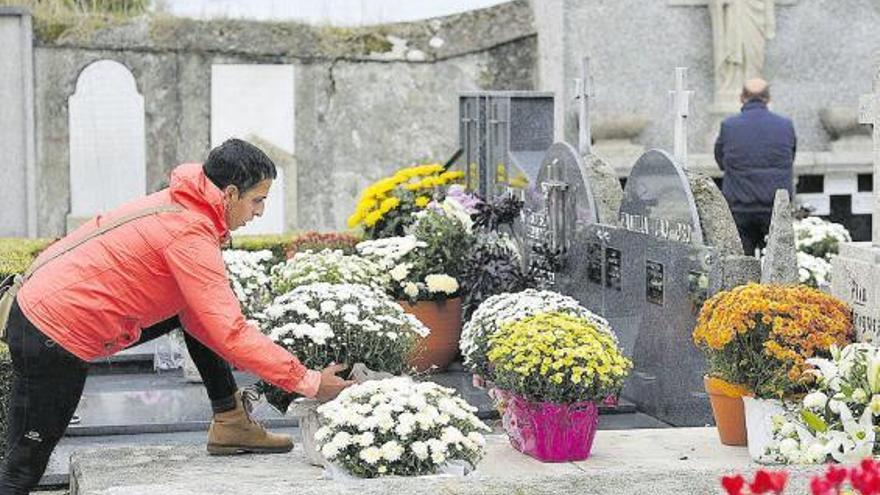 Un joven coloca flores en una sepultura.