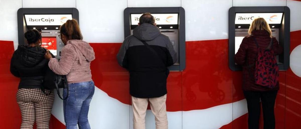 Varias personas sacando dinero esta semana en cajeros automáticos de Ibercaja situados en el centro de la ciudad de Zaragoza.