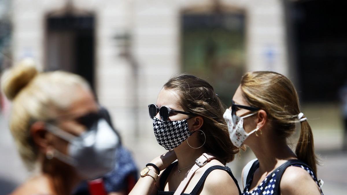 Personas paseando con mascarilla por la calle.