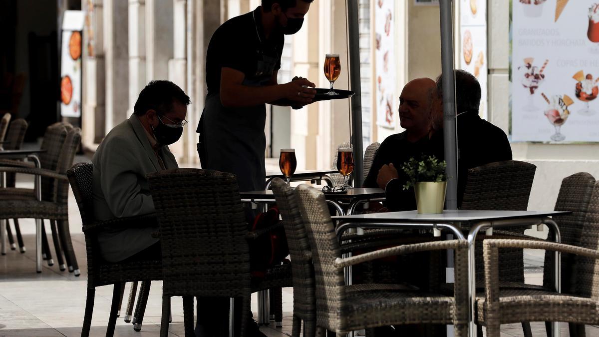 Un camarero sirve unas cervezas en la terraza de un restaurante.