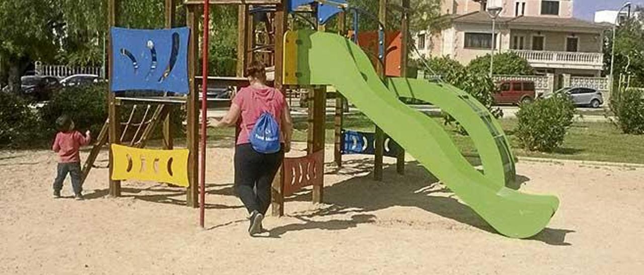 Una madre acompaña a su hijo mientras este utiliza los juegos en uno de los parques de arena.