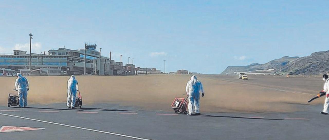 Operarios del aeropuerto de La Palma limpian la ceniza de la pista.
