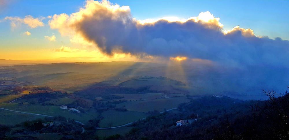 Paisatge. El dia era clar i assolellat, però va créixer una nuvolada i el sol tenia treballs a treure els seus rajos per entremig del núvol i l’horitzó.