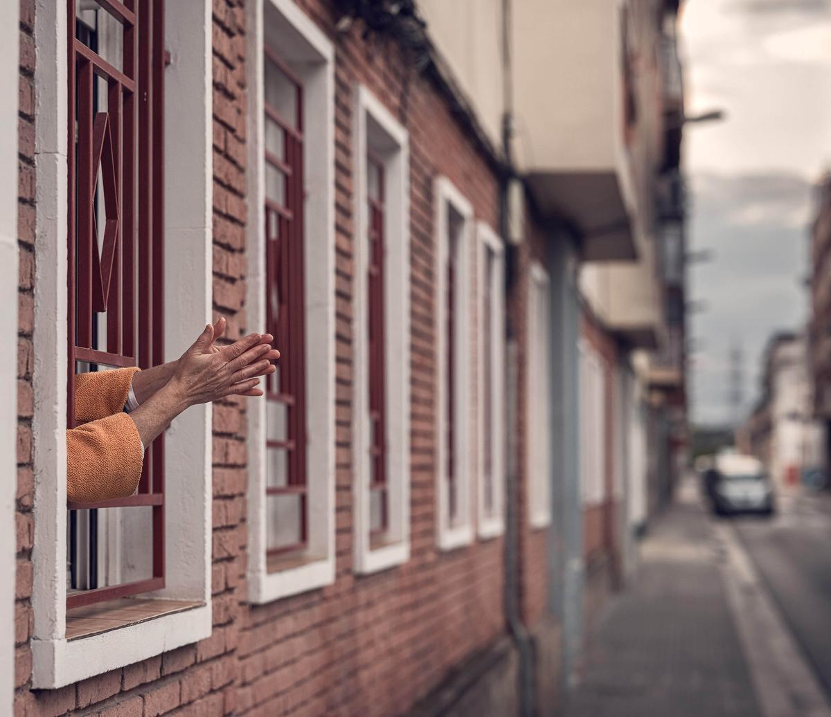 Una mujer aplaude desde su ventana en la calle del Prat.