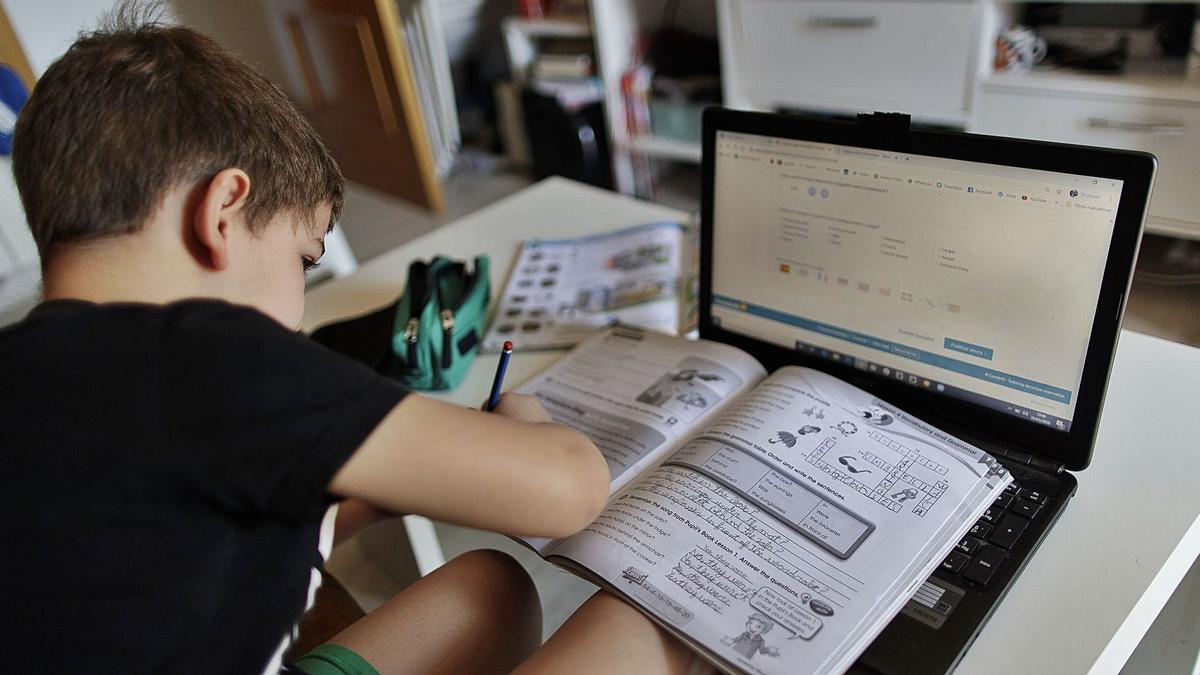 Un niño se organiza para realizar sus deberes en casa, utilizando libro y ordenador.