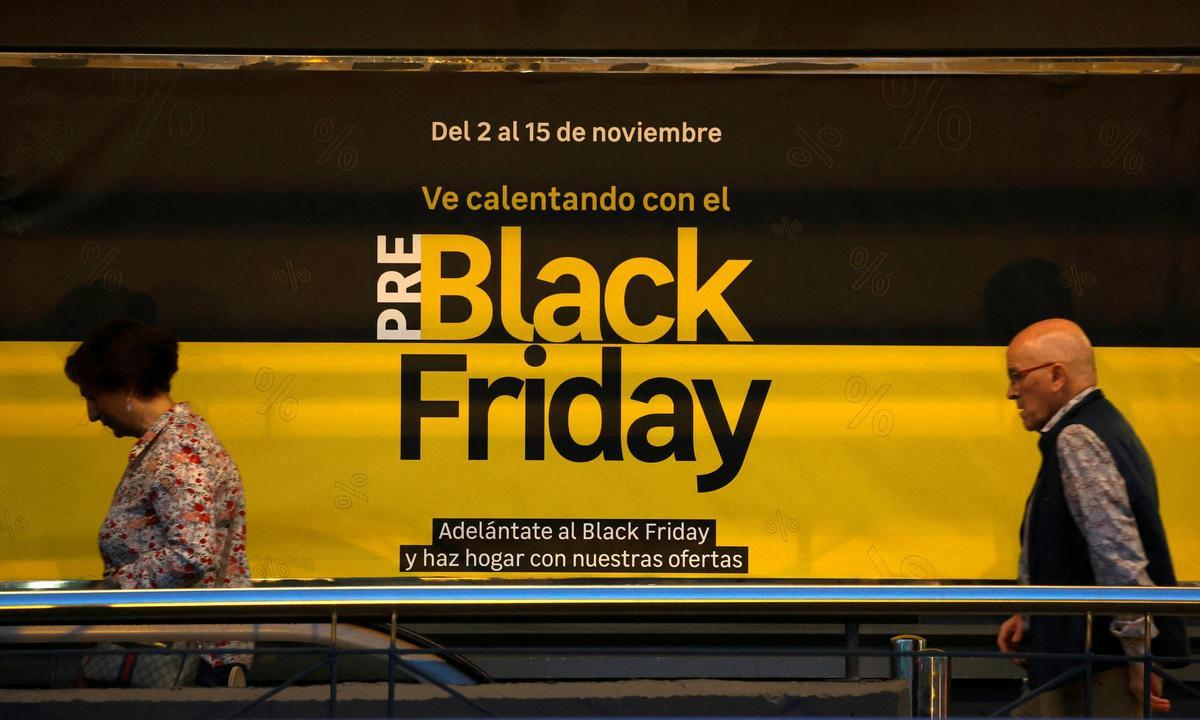 Dos personas pasan ante un anuncio de ofertas del Black Friday en Barakaldo.