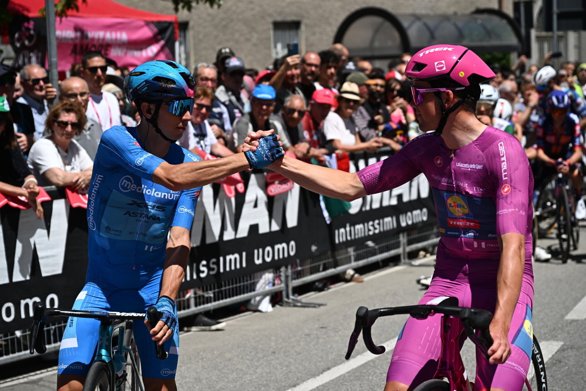 MORBEGNO (Italy), 29/05/2025.- Italian rider Lorenzo Fortunato (L)Â of XDS Astana Team wearing the best climber's blue jersey and Danish rider Mads Pedersen of Team Lidl - Trek wearing the points classification leader's cyclamen jersey, shake hands before the departure of the 18th stage of the Giro d'Italia 2025 cycling race, over 144km from Morbegno to Ceswano Maderno, in Morbegno, Italy, 29 May 2025. (Ciclismo, Italia) EFE/EPA/LUCA ZENNARO