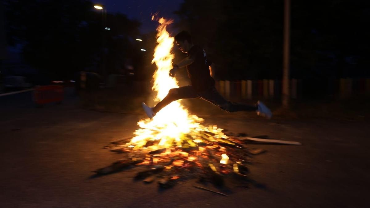 Un hombre cruza de un salto las llamas de una gran hoguera en Vilanova de Arousa.