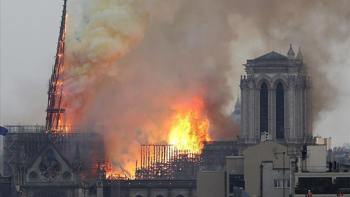 Masas de humo marrón amarillento llenan el aire sobre la catedral de Notre Dame y la ceniza cae sobre los turistas y otros alrededor de la isla que marca el centro de París.