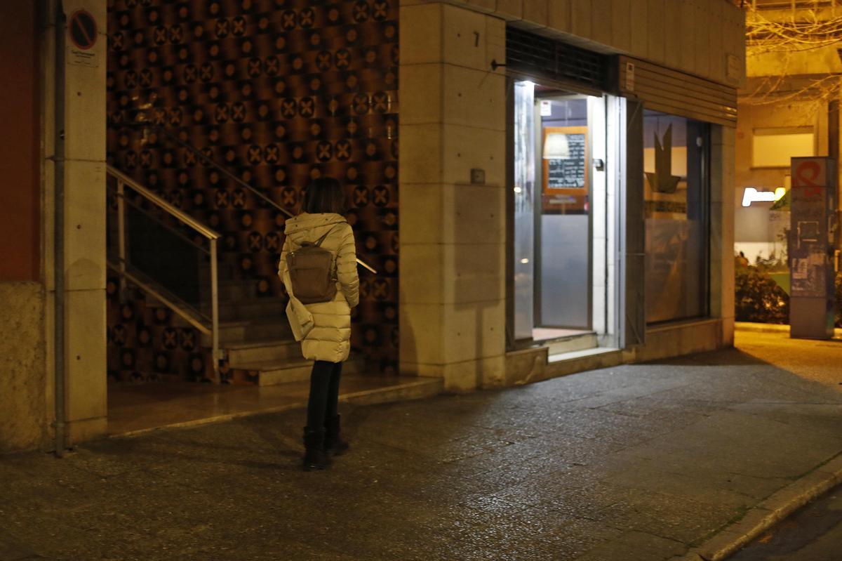 Una dona camina per un carrer de Girona, de nit.