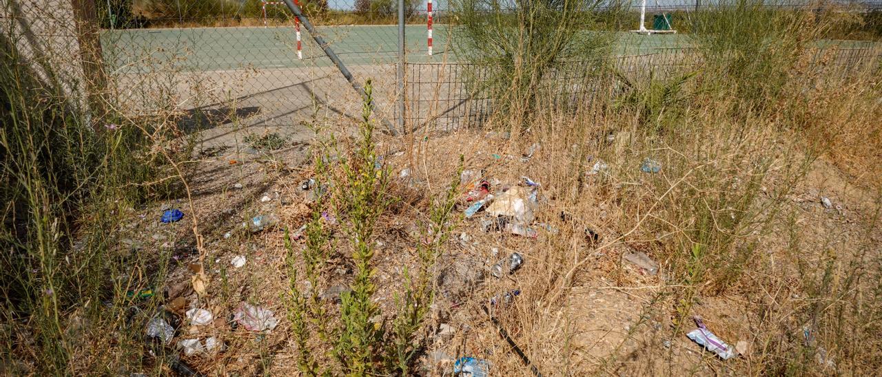 Suciedad y malas hierbas junto a la pista deportiva.