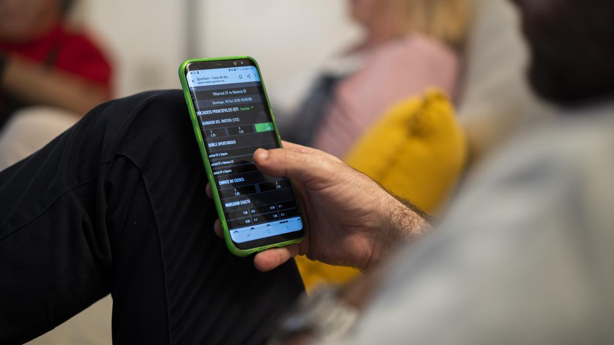 Un joven apuesta a un resultado deportivo con el teléfono móvil.