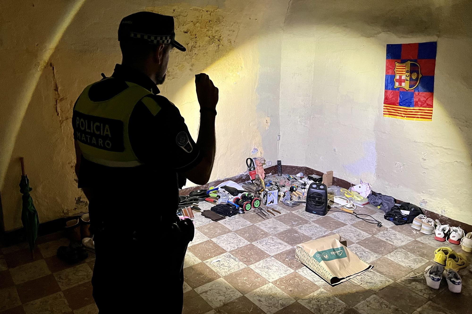 Un agente de la Policía Local de Mataró inspecciona las pertinencias de un okupa en el inmueble donde vive, al lado del centro de la ciudad