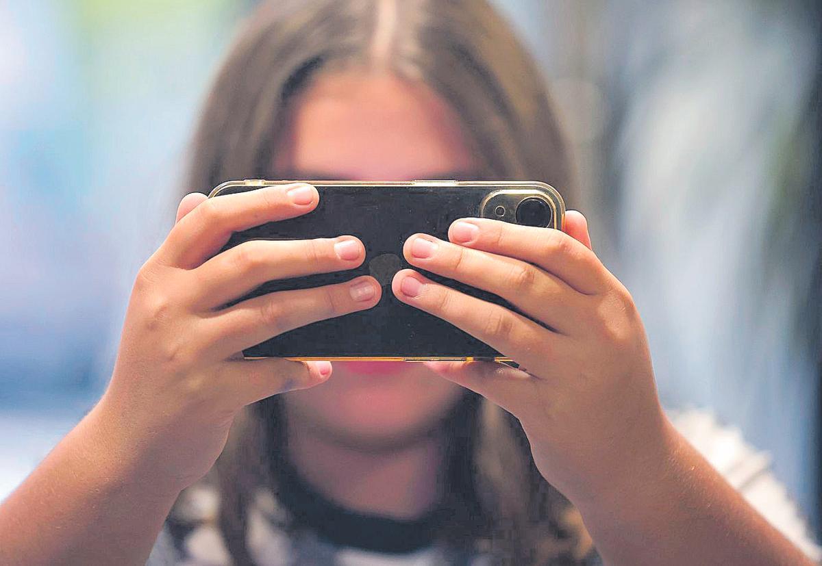 Una joven observa la pantalla de su móvil