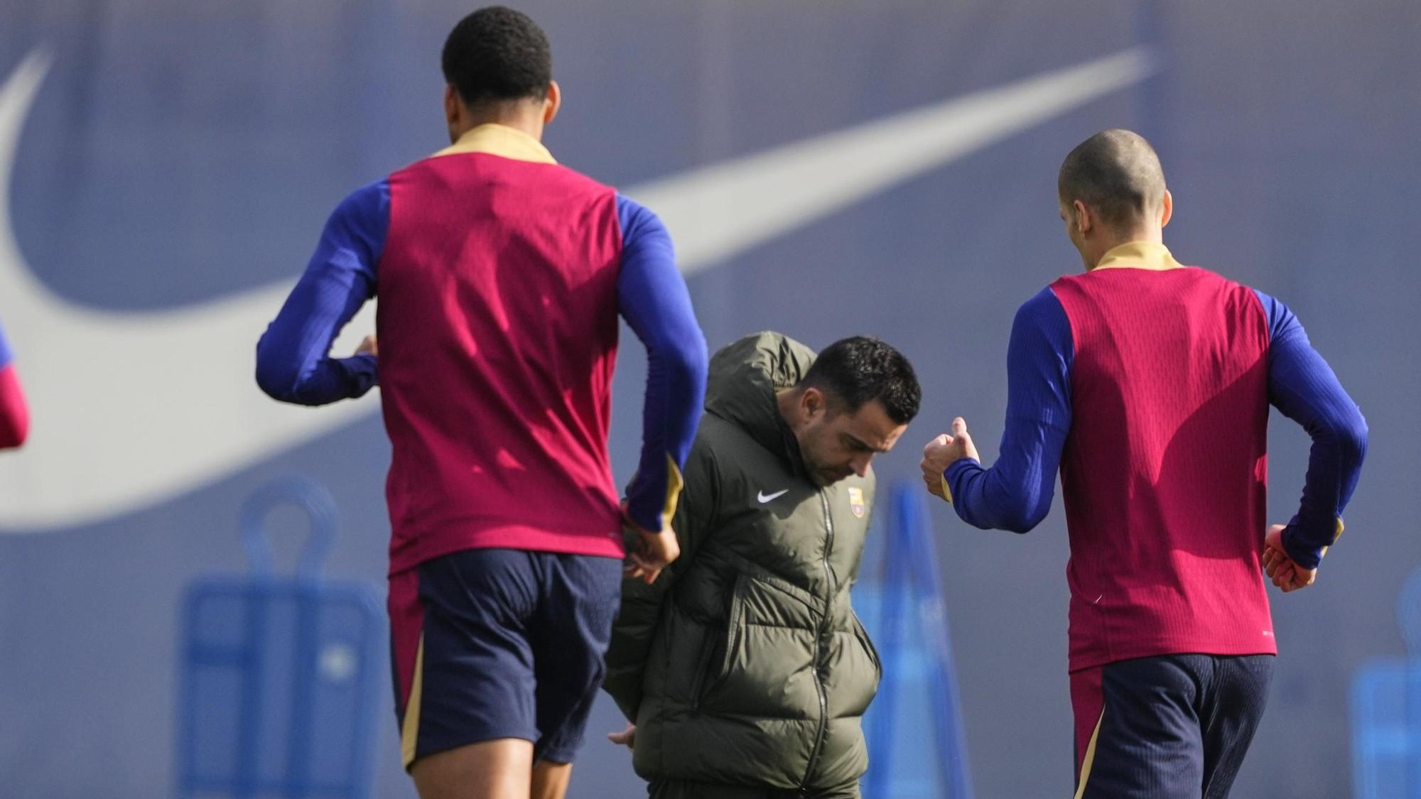 Xavi camina pensativo durante el calentamiento de sus jugadores.