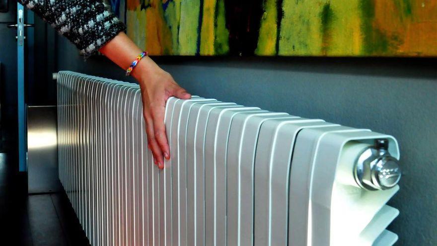 Una mujer comprueba el calor que emana de un radiador.