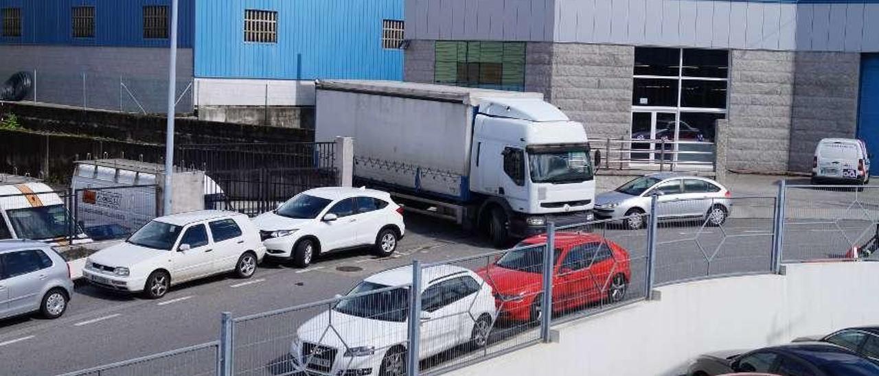 Los vehículos mal aparcados en la calle sin señalización impiden la salida de un camión. // FdV