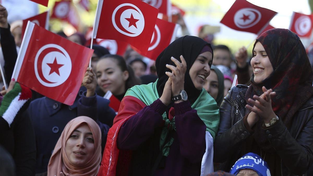 Varias mujeres ondean banderas nacionales durante la celebración del quinto aniversario de la caída de la dictadura de Ben Ali en Túnez.