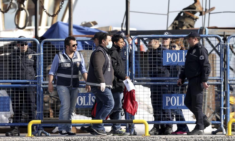 Refugiados son escoltados abordo de un ferri en el puerto de Mytilene en la isla de Lesbos