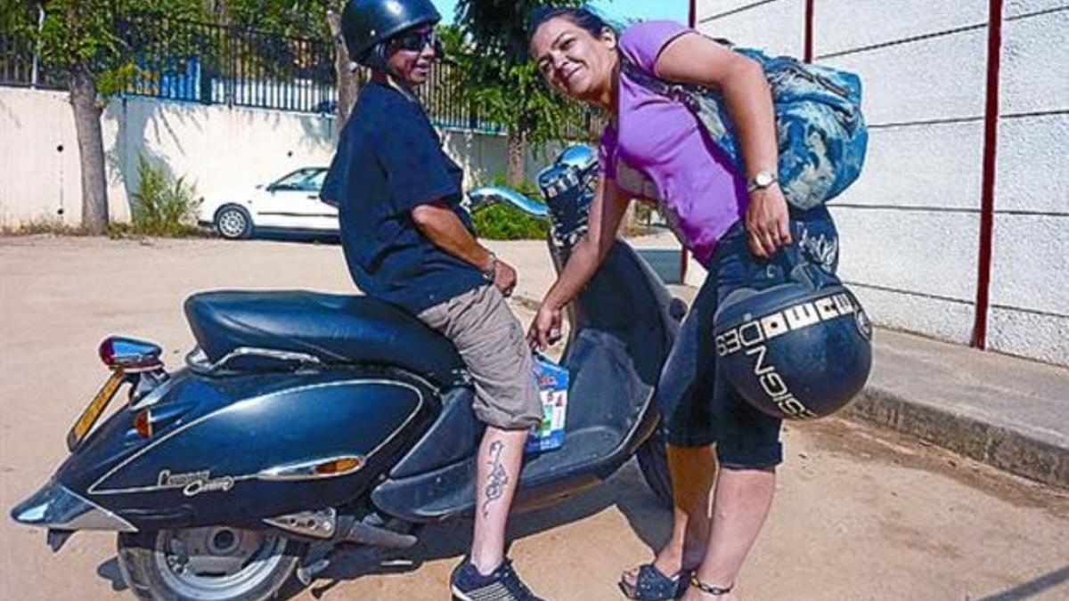 Maite Calvo carga un cartón de leche en la moto de su amiga Susi.