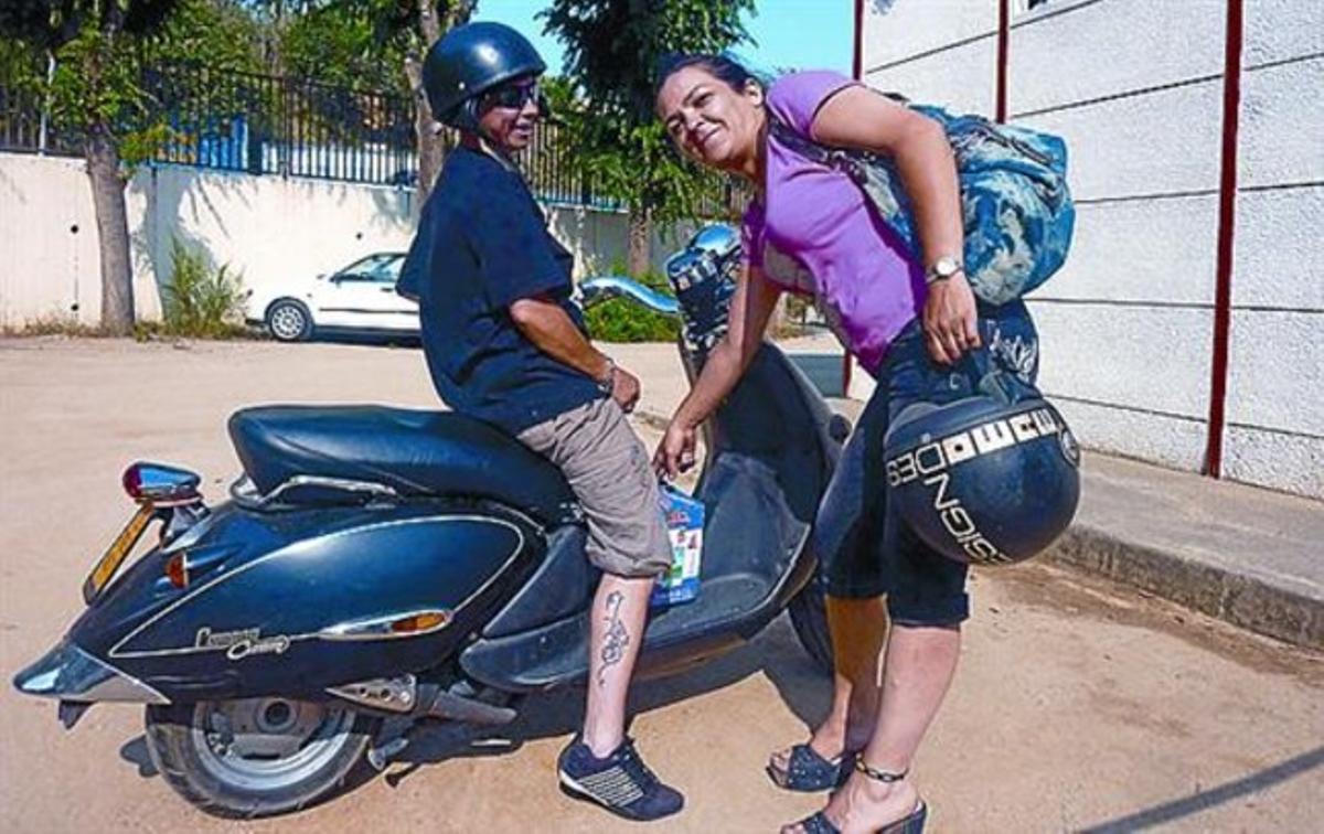 Maite Calvo carrega un cartró de llet a la moto de la seva amiga Susi.