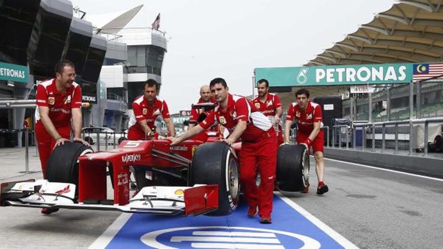 Los mecánicos del «cavallino» llevan el monoplaza de Fernando Alonso al garaje de Ferrari en el circuito de Sepang.